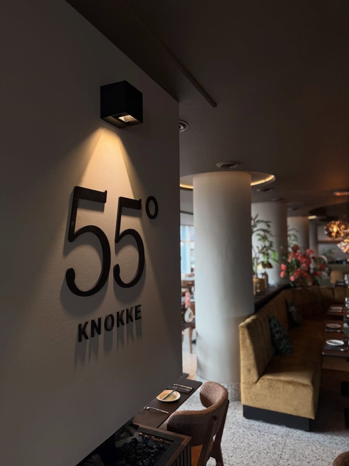 Verlicht 55°-logo aan de wand, aangestraald door een zwarte wandspot