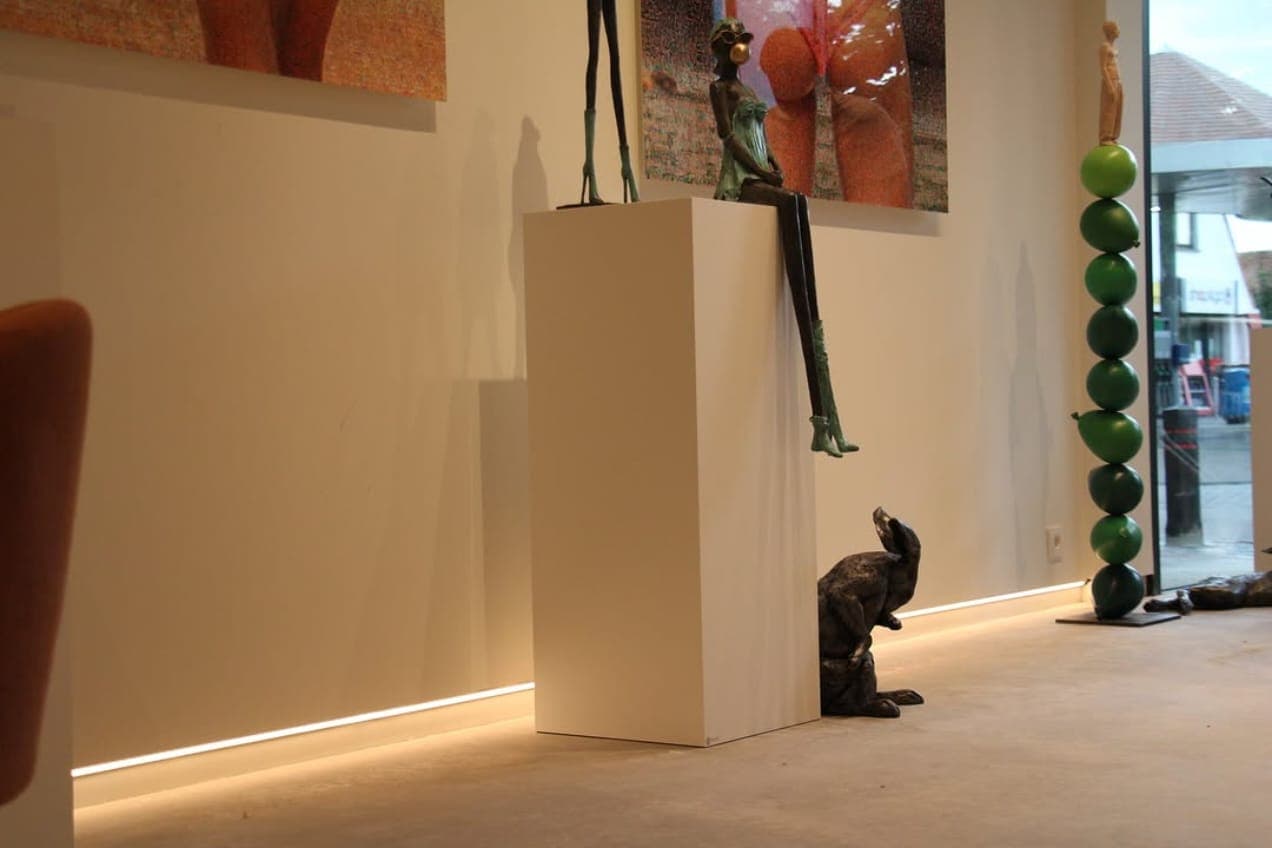 Bronzen beeld op een witte sokkel met een indirecte ledstrip die langs de vloer meeloopt
